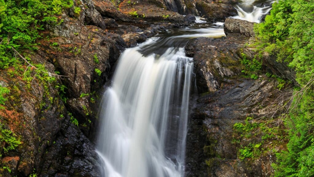 The cascading waterfall at Moxie Falls in summertime near The Lodge at Moosehead Lake