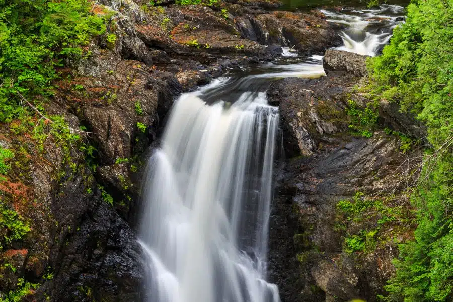 The cascading waterfall at Moxie Falls in summertime near The Lodge at Moosehead Lake