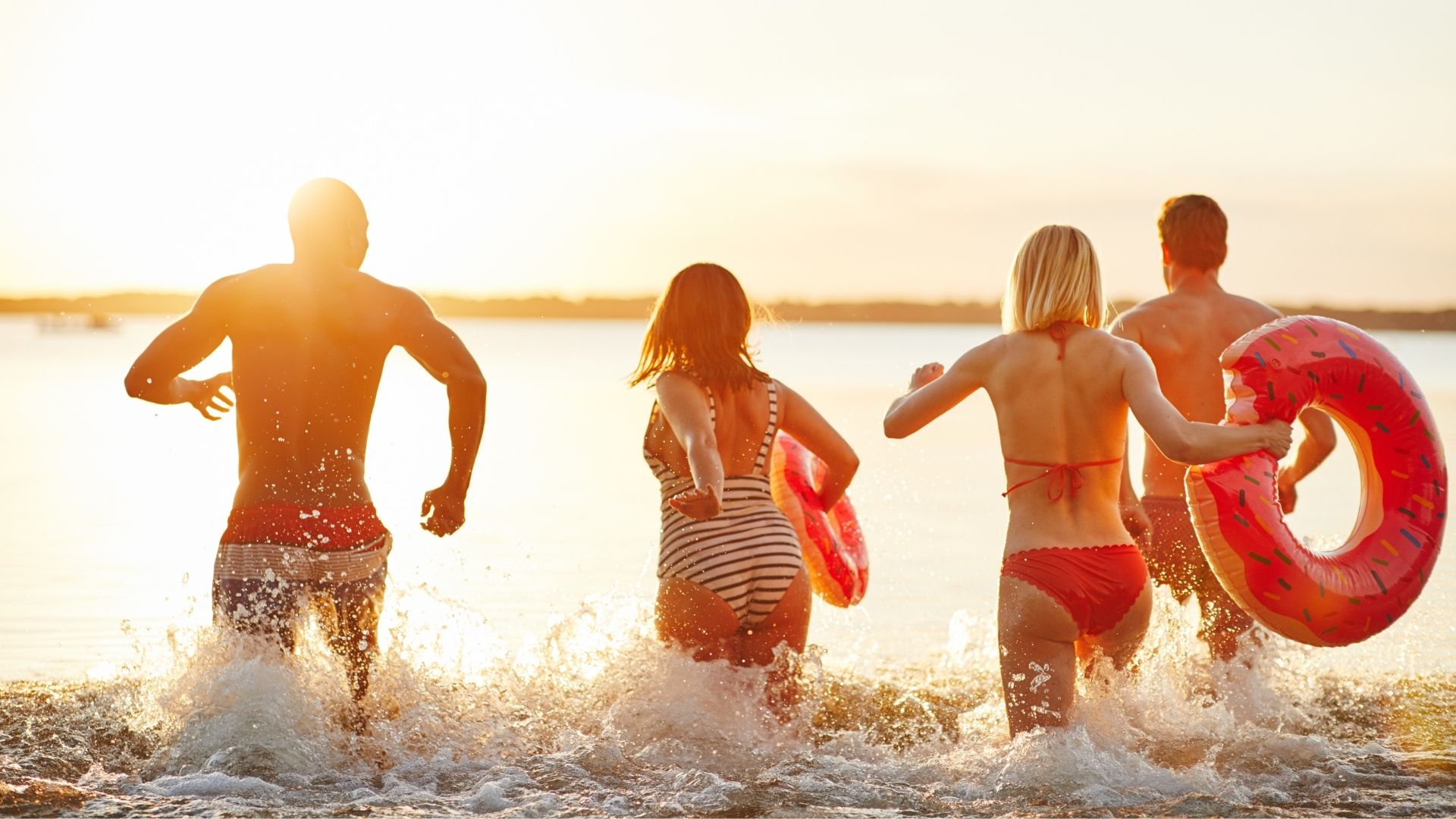 two couples running in a lake at sunset