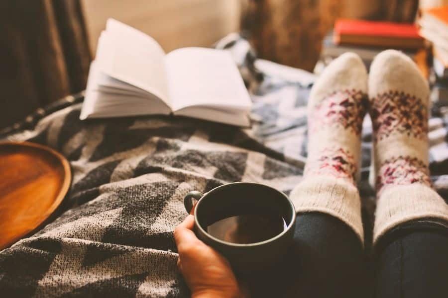 cozy socks with hot cocoa and open book