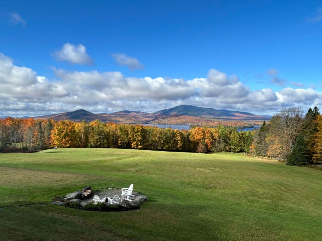 Fall foliage at Moosehead Lake seen from the Lodge's lawn, with Mount Kineo and colorful shoreline in the distance